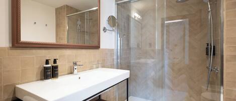 Une salle de bain moderne avec une douche à parois de verre, un grand miroir et un lavabo blanc.