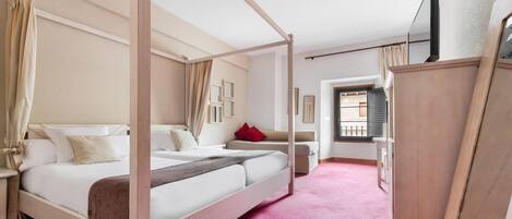 A four-poster bed with a wooden frame, a red carpet, and a wooden wardrobe.