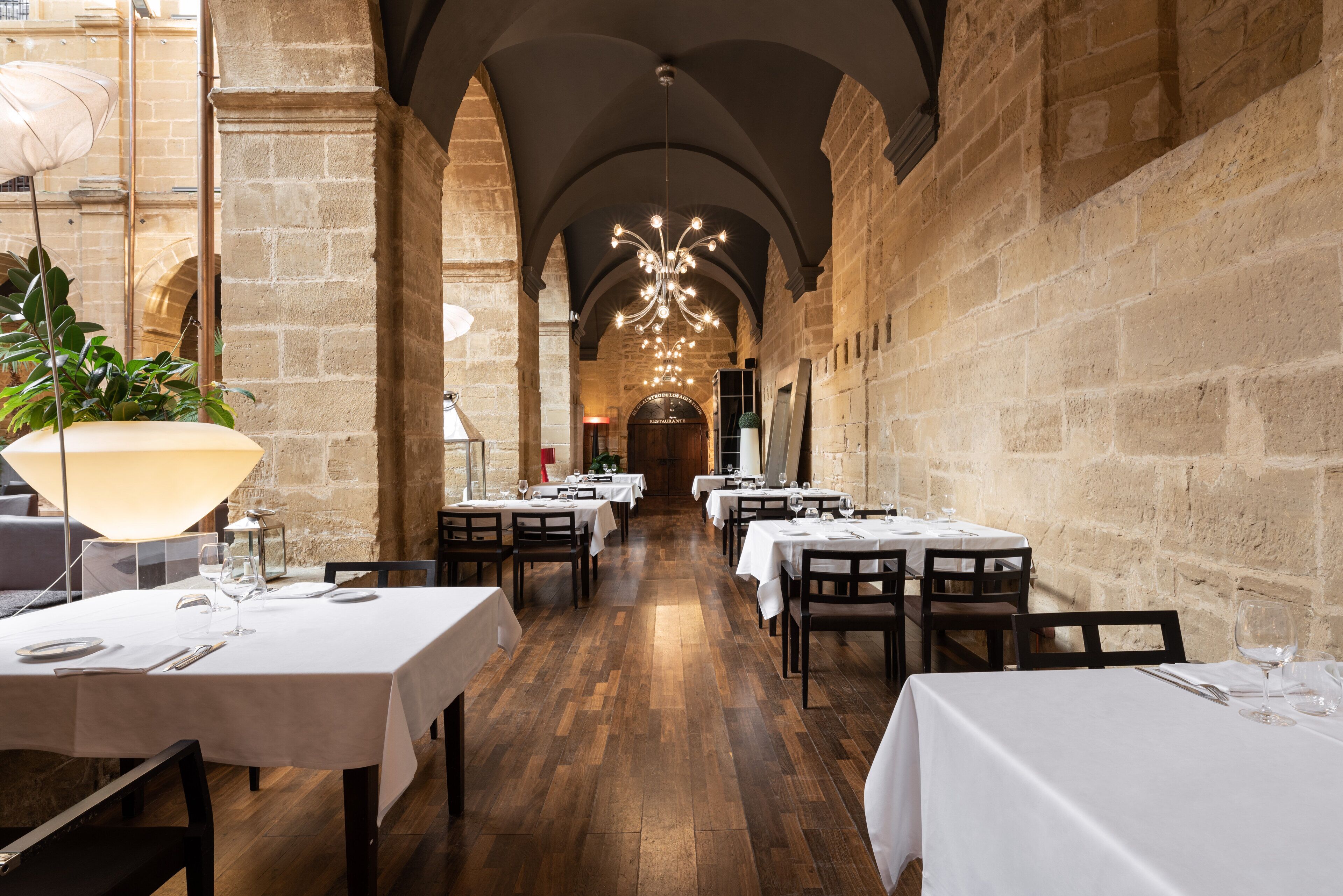 Een restaurant met gedekte tafels, een kroonluchter en stenen muren.