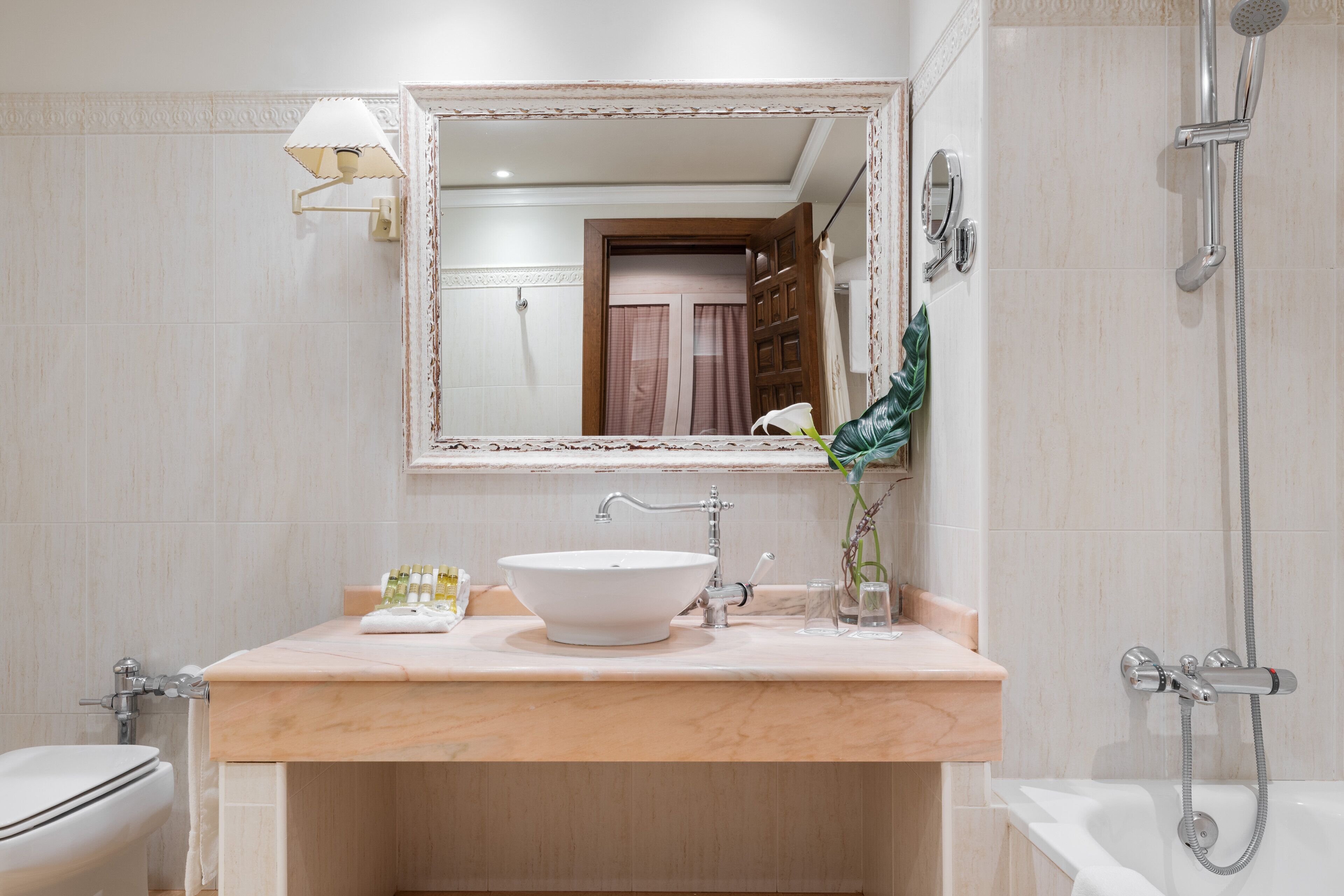 A bathroom with a white sink, a mirror, a shower, and a toilet.