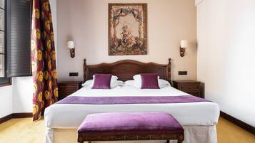 Una cama bien hecha con una colcha y almohadas moradas, un cabecero de madera y un banco al pie de la cama.