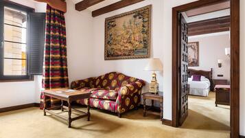 Una habitación con un sofá estampado, una mesa de madera, una lámpara y un cuadro en la pared.