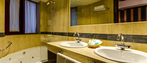 Un baño con bañera, dos lavamanos y un espejo grande.