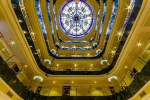 A multi-level atrium with a central stained glass dome, multiple balconies, and a marble floor. - Hotel Infanta Cristina (Jaén)