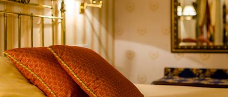 A bed with two pillows, a lamp, and a mirror on the wall.
