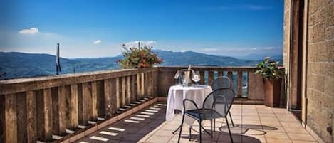 Un balcón con mesa y sillas, con vistas a un paisaje montañoso.