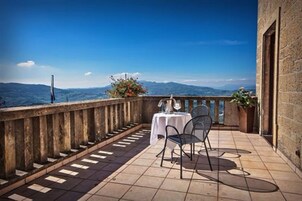 Un balcón con mesa y sillas, con vistas a un paisaje montañoso.