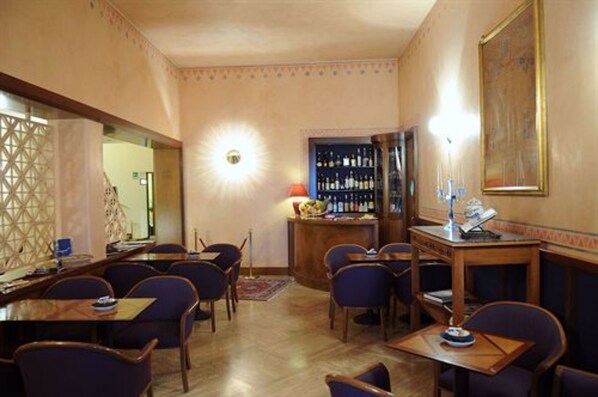 Un comedor con mesas y sillas, una barra con botellas y una pared decorativa.