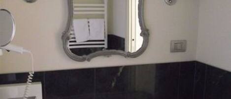 A bathroom with a white sink, a mirror with an ornate frame, and two wall-mounted lights.