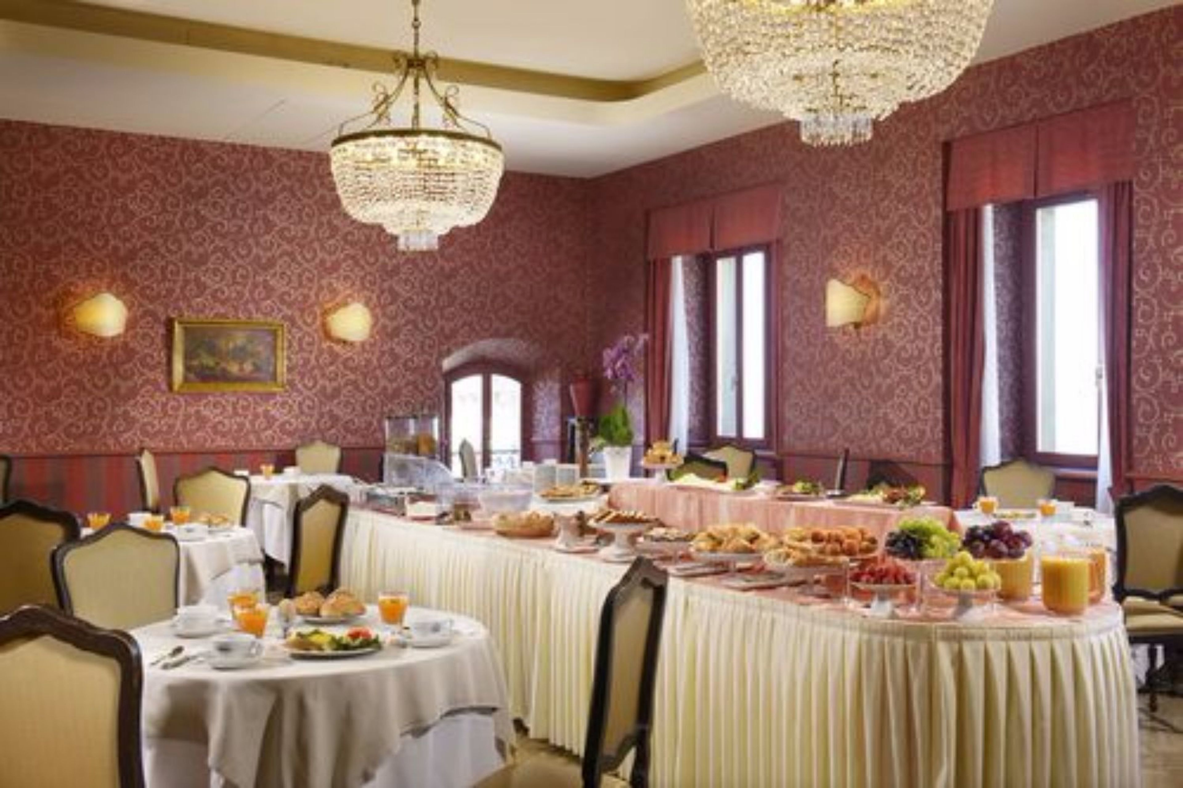 Comedor con mesas redondas dispuestas para el desayuno, con una variedad de alimentos y bebidas.