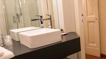 A bathroom with two white sinks, a black countertop, a glass shower enclosure, and a white door.