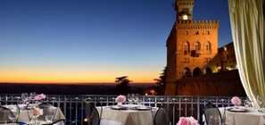 A restaurant with tables set for dining, overlooking a historic tower. - Hotel Titano (San Marino)