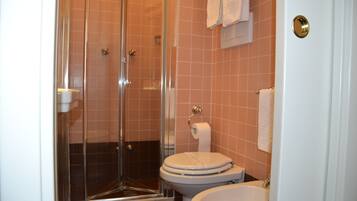 A bathroom with a glass shower enclosure, a toilet, and a sink.
