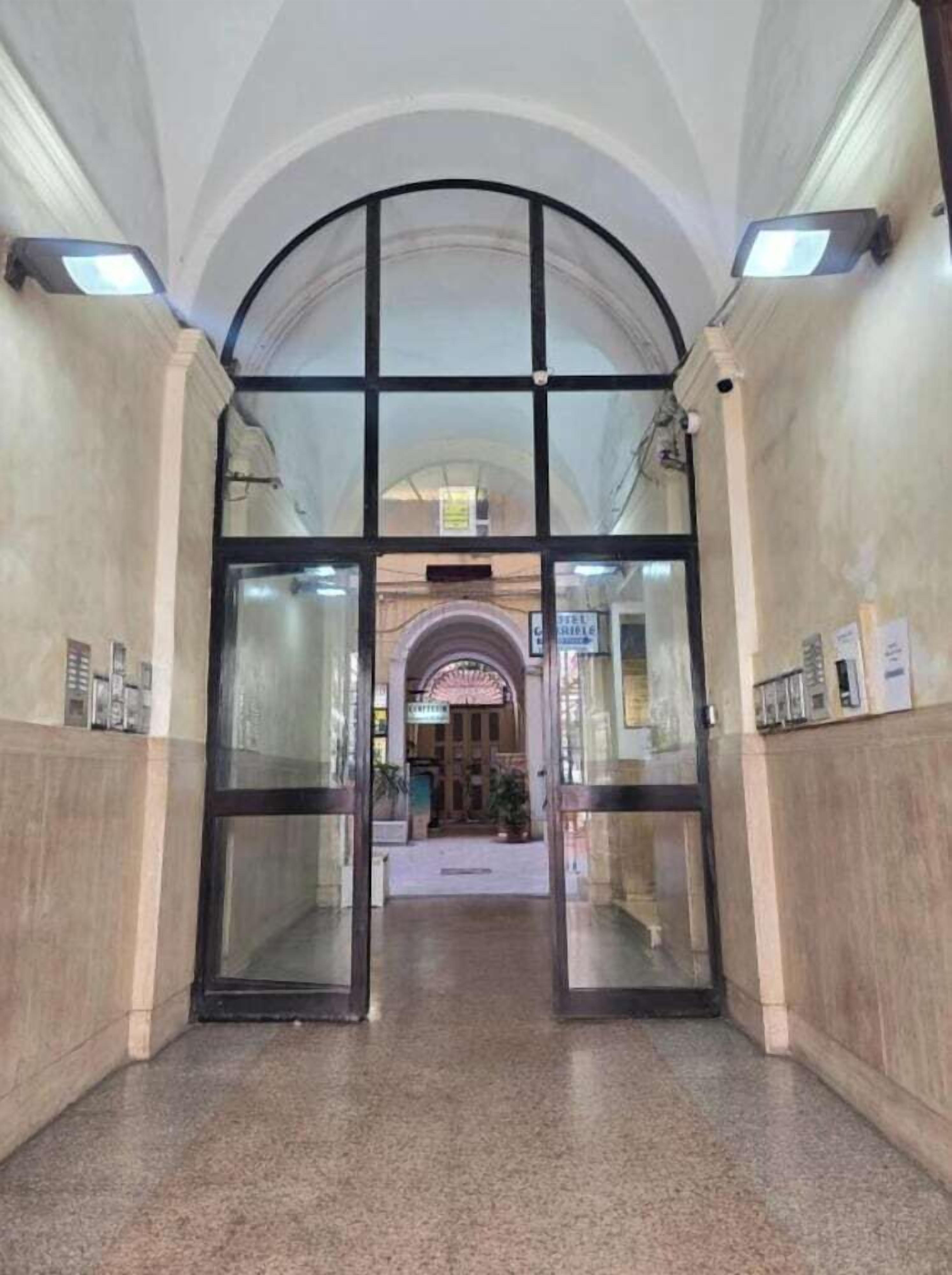 A hotel entrance with a glass door, a tiled floor, and a sign indicating a restaurant.