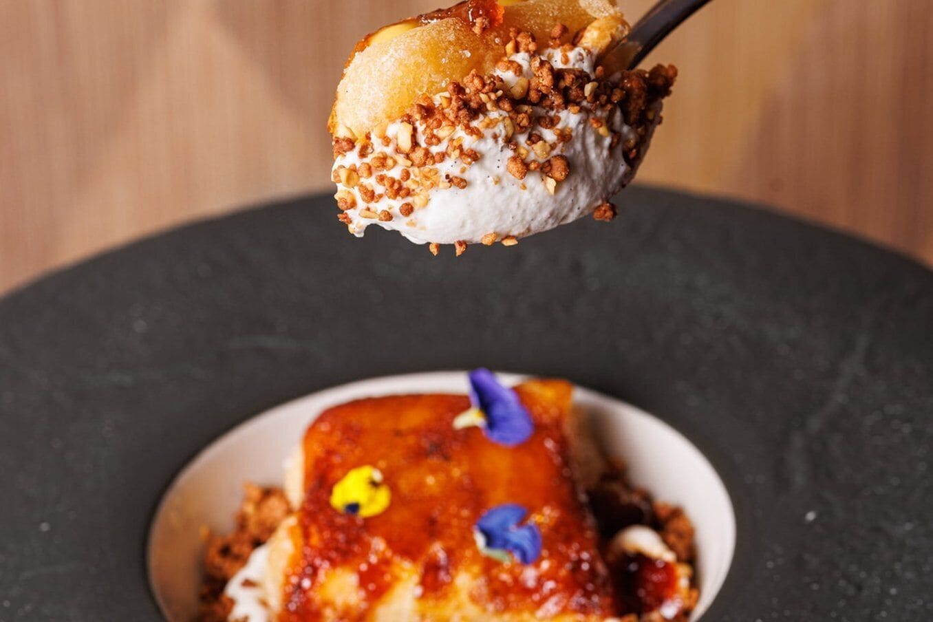 Postre amb una bola de gelat coronada amb nous triturats i salsa de caramèl.