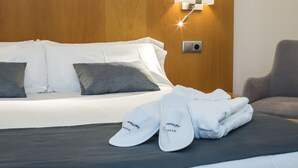 A hotel room with a bed, pillows, a nightstand, a lamp, and a chair.