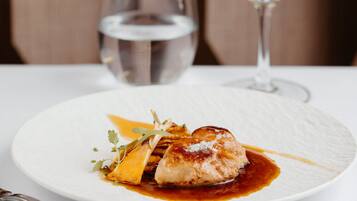 A plate of food with a glass of white wine and a glass of water on a table.