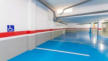 A parking garage with blue and white floors, red and white walls, and a disabled parking sign.