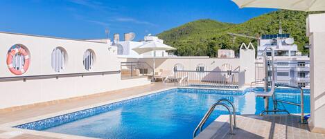 A rooftop swimming pool with lounge chairs and a lifebuoy.
