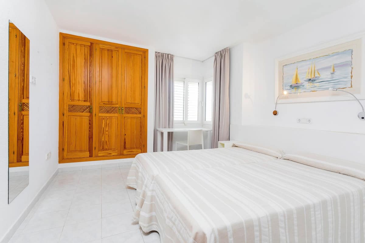 Un dormitorio con cama, escritorio y un amplio armario de madera.