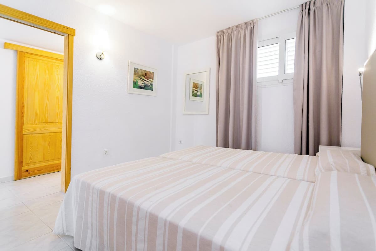 Un dormitorio con cama, puerta de madera y dos cuadros en la pared.