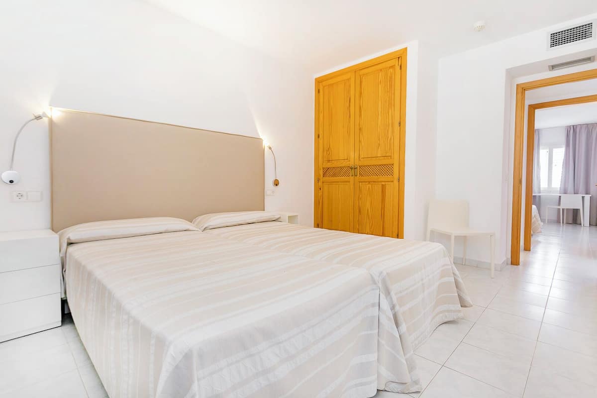 Un dormitorio moderno con una cama grande, un armario de madera y un escritorio con una silla.