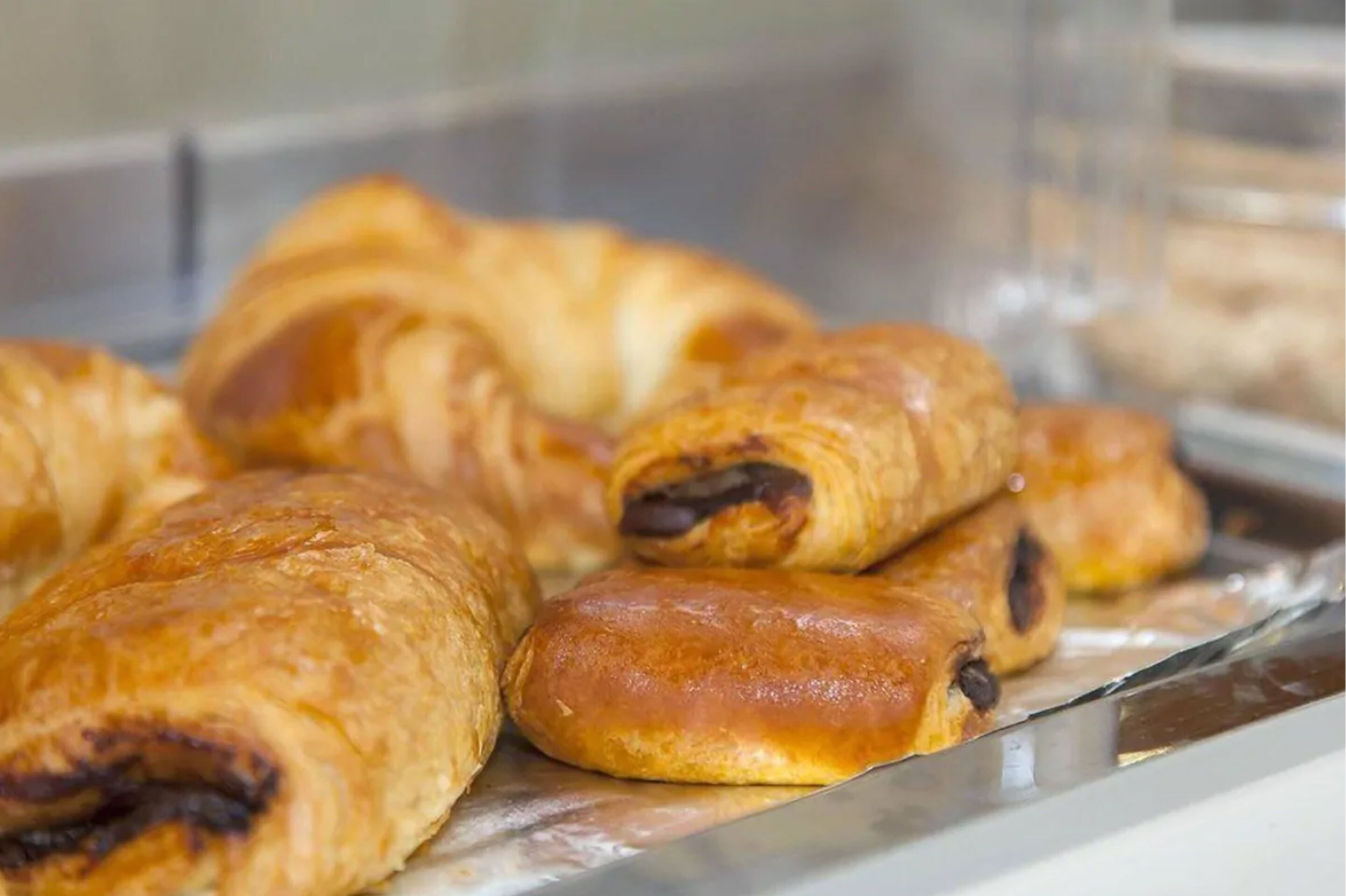 Una bandeja de metal con pasteles, incluyendo croissants y hojaldres rellenos de chocolate.