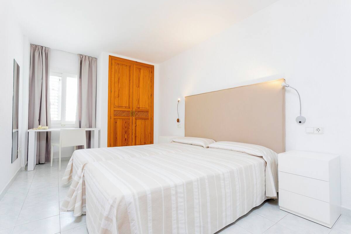 Un dormitorio con cama, mesita de noche y armario.