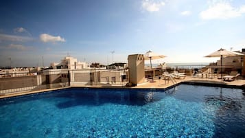 Una piscina al aire libre, sombrillas, tumbonas