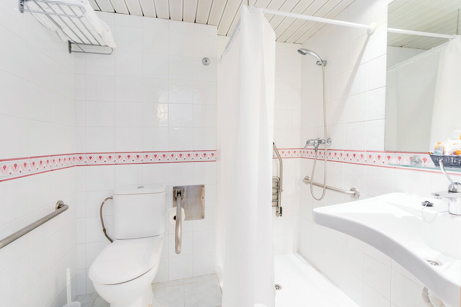 A bathroom with a toilet, shower, and sink.
