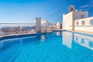 Una piscina al aire libre, sombrillas, tumbonas