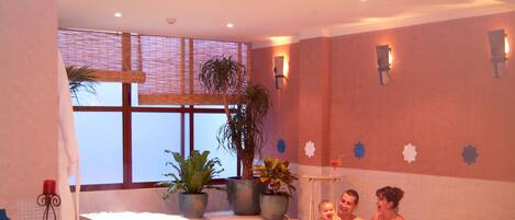 Un baño tipo spa con dos tinas grandes, plantas en macetas y azulejos decorativos.