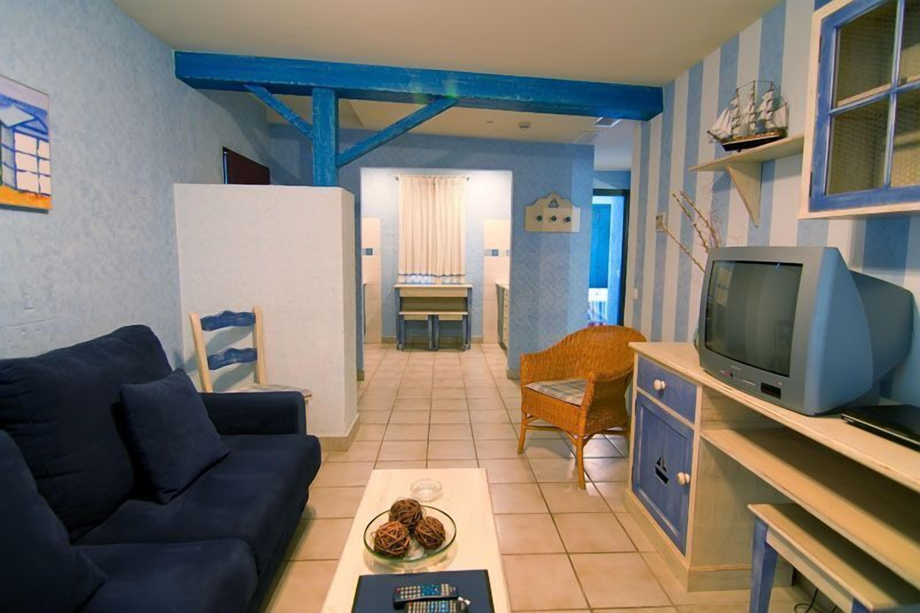 A compact living space with a sofa, a television, and a dining area with a table and chairs.