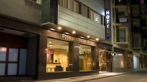 Un hôtel doté d’une façade moderne, de grandes fenêtres en verre et d’une enseigne « HÔTEL » bien visible au-dessus de l’entrée.