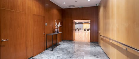 A hallway with wooden paneling, a marble floor, and a reception desk with a vase of flowers.