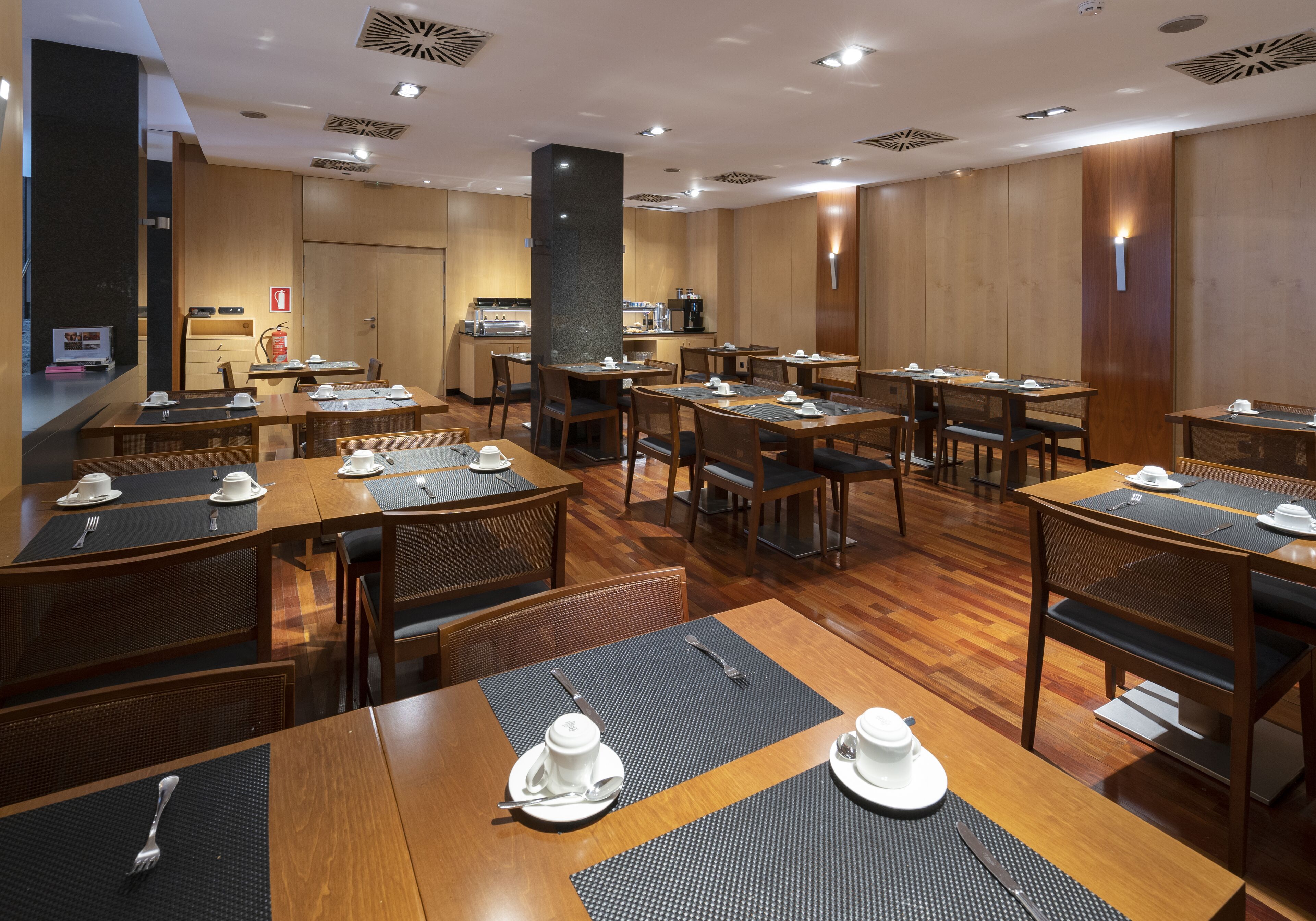 Un comedor de hotel con varias mesas y sillas, equipado con vajilla y una estación de café.