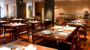 Un restaurant avec des tables et des chaises en bois, un comptoir avec une machine à café et une vue sur la rue.