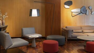 Un salon moderne comprenant un canapé, des fauteuils, des poufs, une lampe sur pied et une table d’appoint.