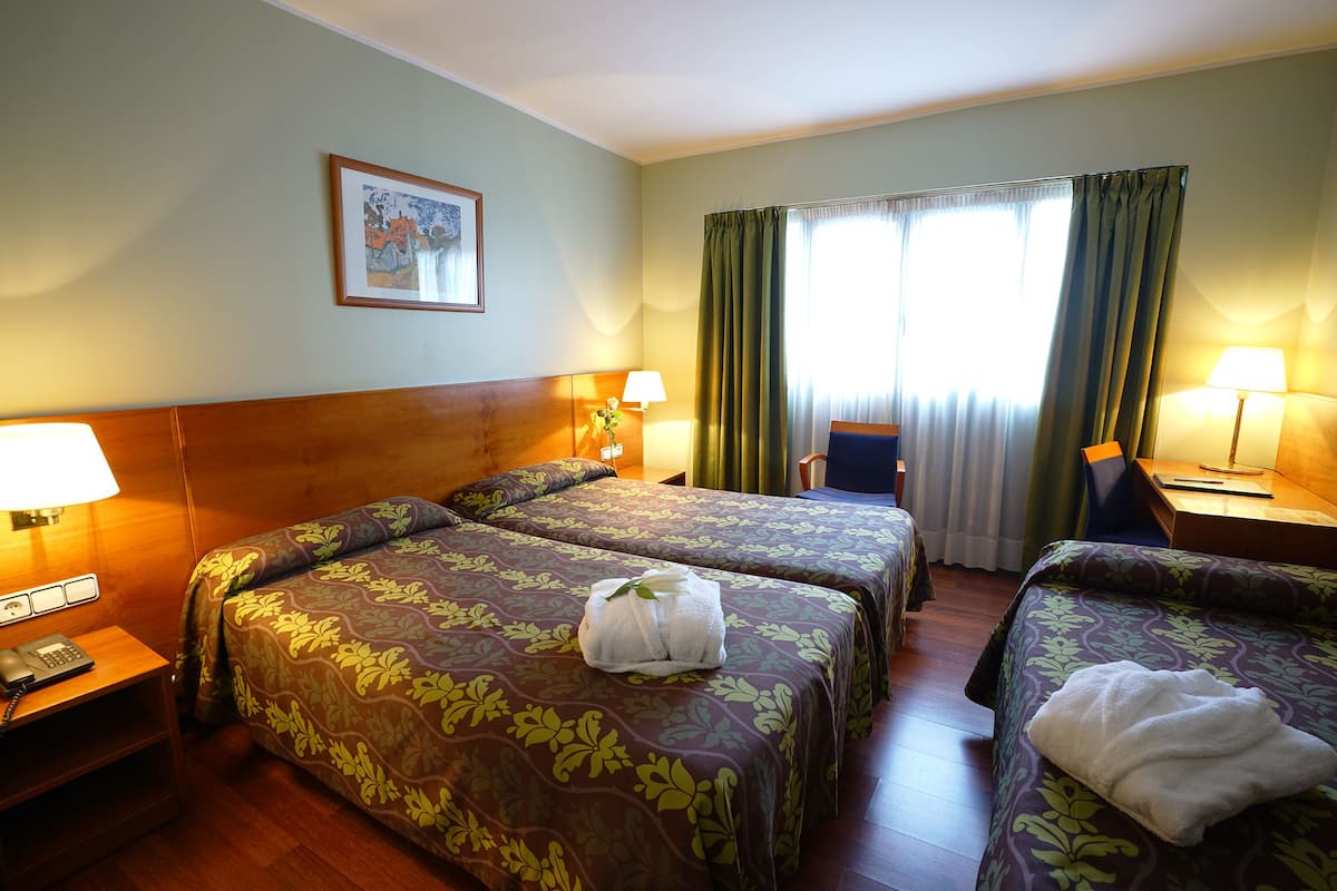 Une chambre d’hôtel avec deux lits, un bureau, une chaise et un tableau au mur.