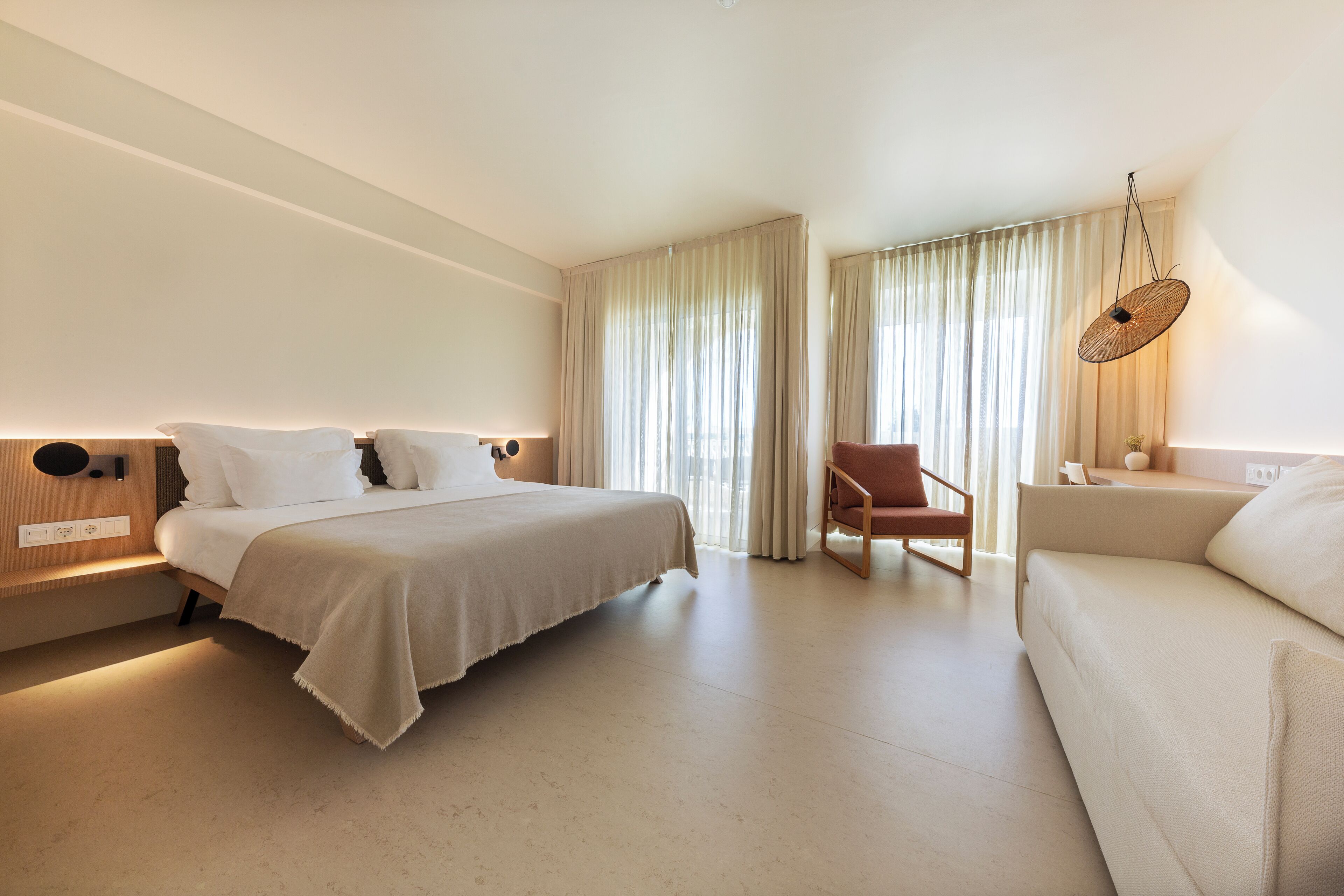 Una habitación de hotel moderna con una cama grande, un sofá, una silla y un escritorio.