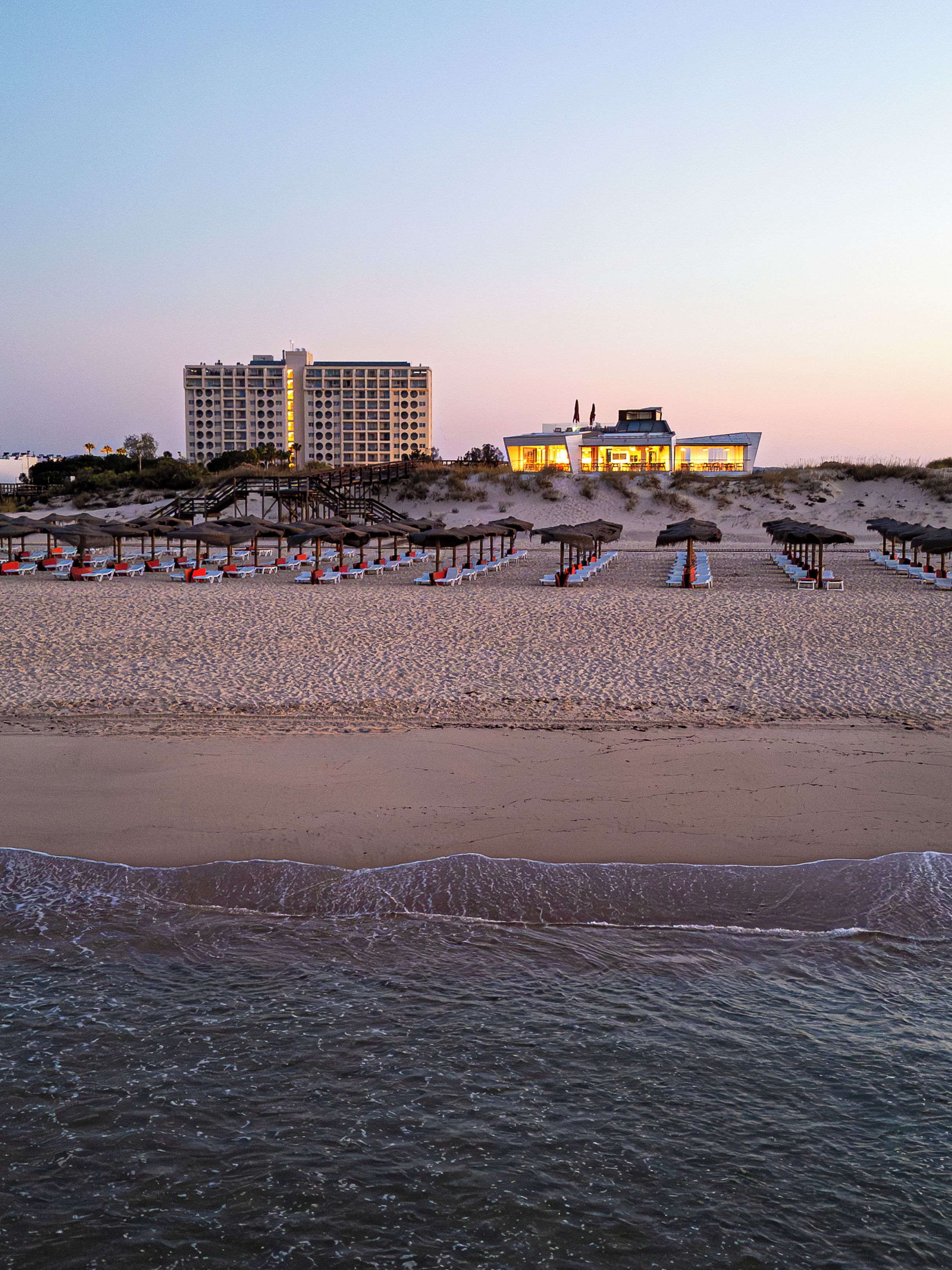 Uma praia com um hotel e guarda-sóis.