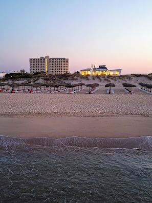 Una playa con un hotel y sombrillas.