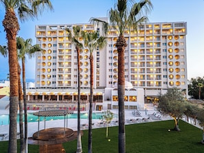 Un hotel con varios pisos, piscina y palmeras.