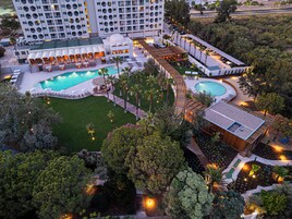 A hotel with multiple swimming pools, a rooftop bar, and a landscaped garden.