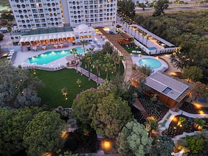 Un hotel con múltiples piscinas, un bar en la azotea y un jardín ajardinado.