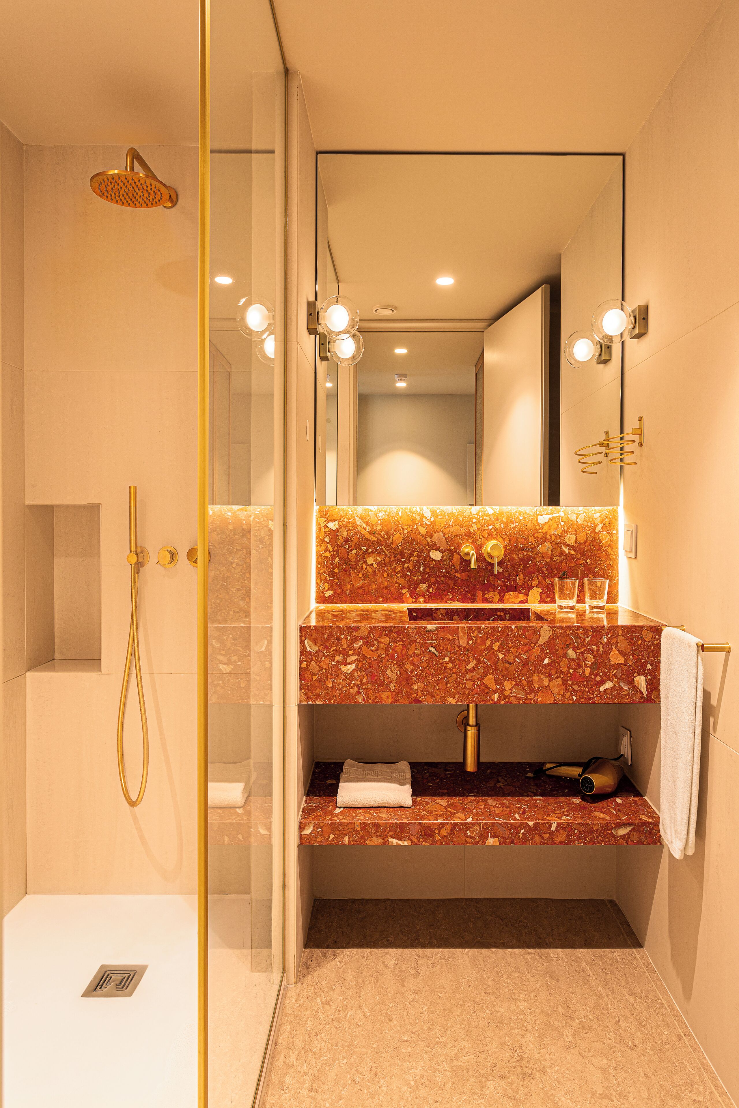 Un bany modern amb dutxa envidriada, un lavabo de marbre i un suport per a tovalloles.