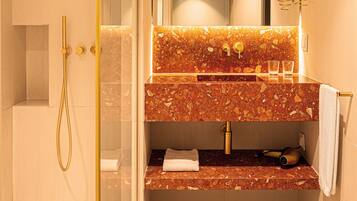 Un bany modern amb dutxa envidriada, un lavabo de marbre i un suport per a tovalloles.