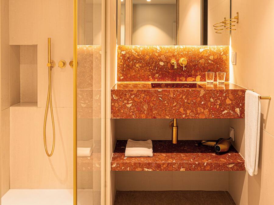 Un bany modern amb dutxa envidriada, un lavabo de marbre i un suport per a tovalloles.