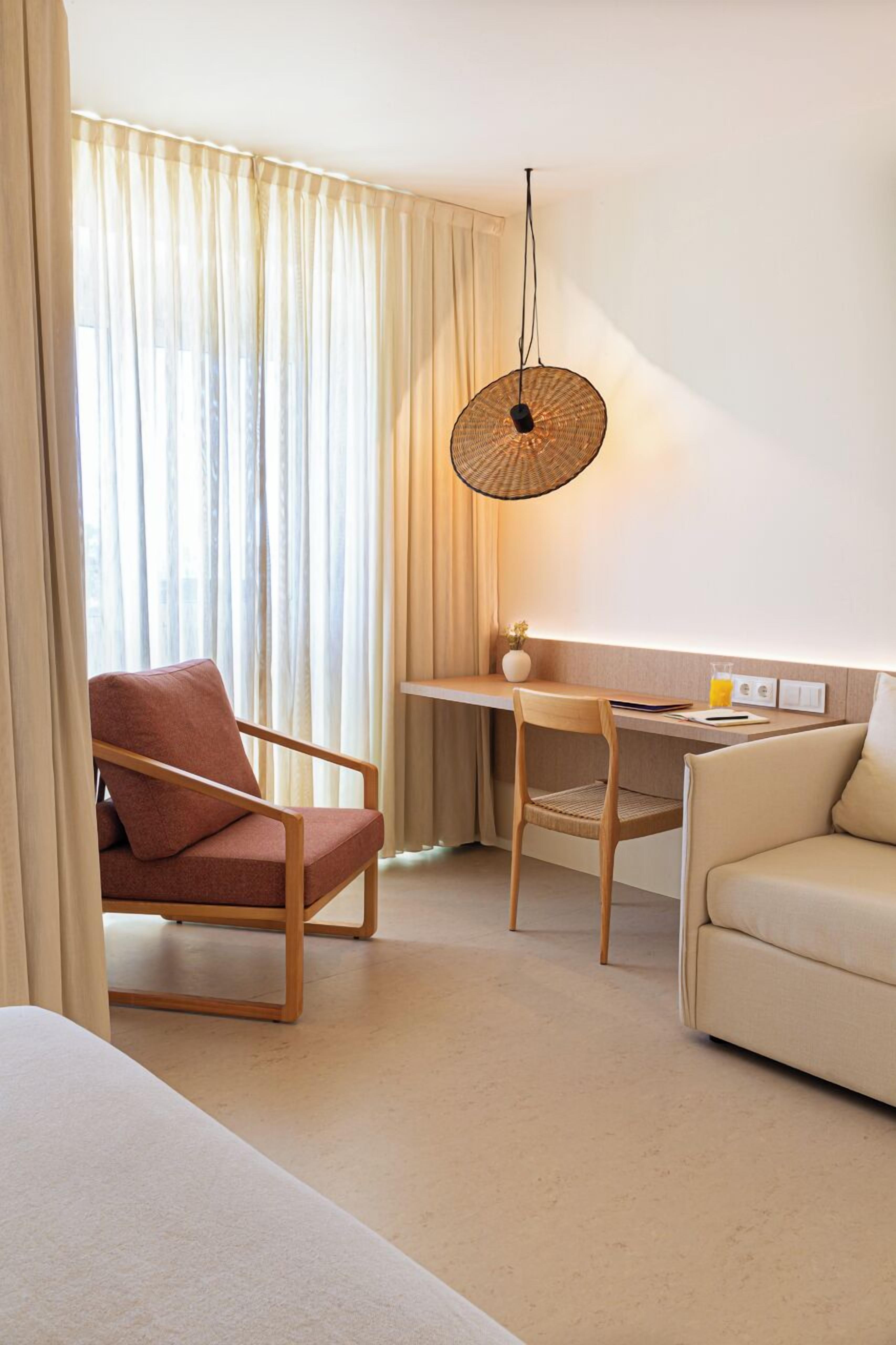 Een hotelkamer met een bed, een bureau, een stoel en een bank.