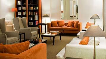 A modern living room with a sofa, armchairs, a coffee table, and a bookshelf.